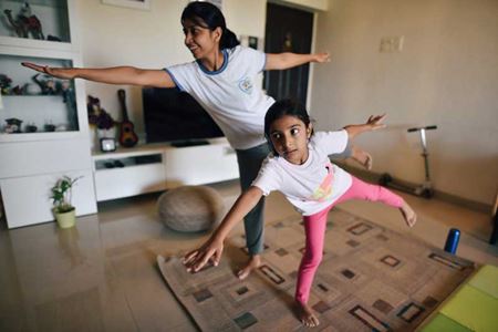 Mamá e hija haciendo una postura de equilibrio de yoga